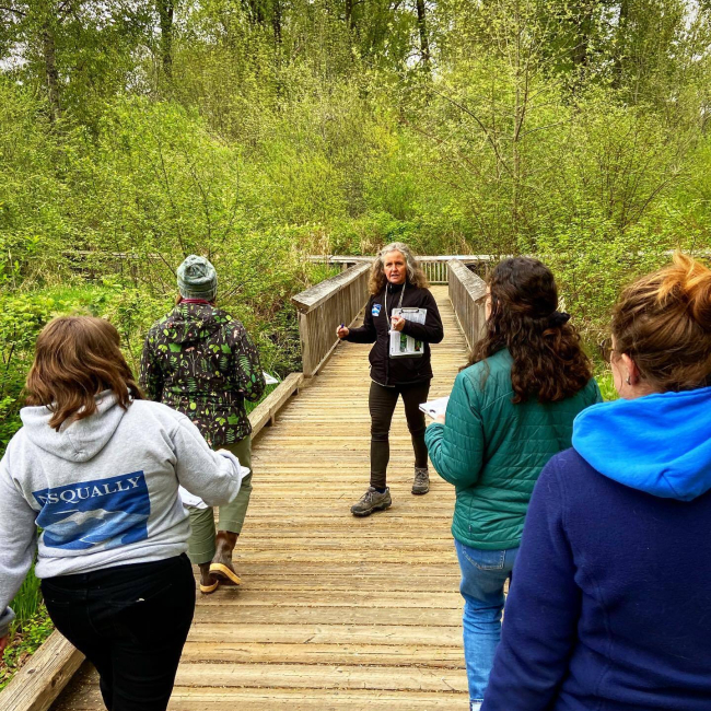 Sheila Wilson leads a group down a boardwalk surrounded by lush vegetation.