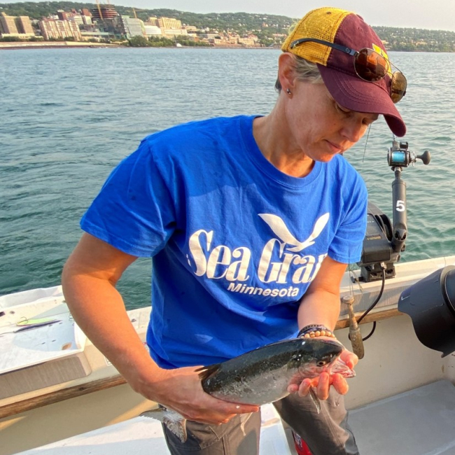 Amy Schrank holding a coho salmon caught outside Duluth Harbor in Lake Superior.