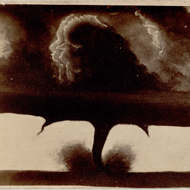 A black and white photo of a tornado with multiple vortices, one in the center, which reaches to the ground and a smaller one on either side which do not reach the ground.