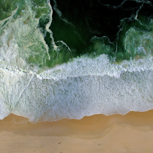 Aerial view of waves crashing on a sandy beach.
