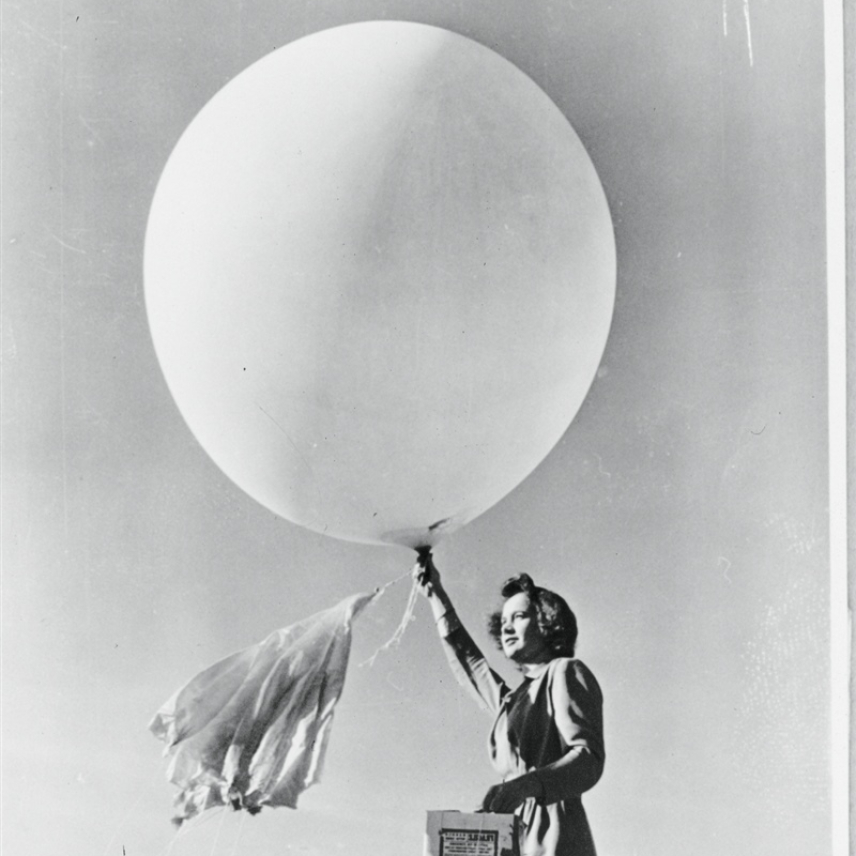 Black and white photo of a woman launching a weather balloon. 