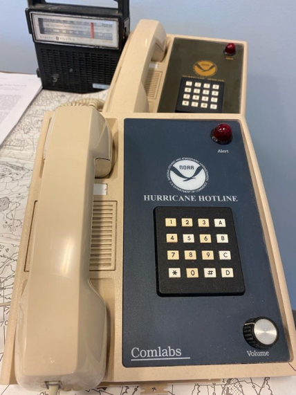 Photo of a beige push button phone with a NOAA emblem and the words "Hurricane Hotline" above the buttons. The red light indicated a call was coming in or a caller was on the line.